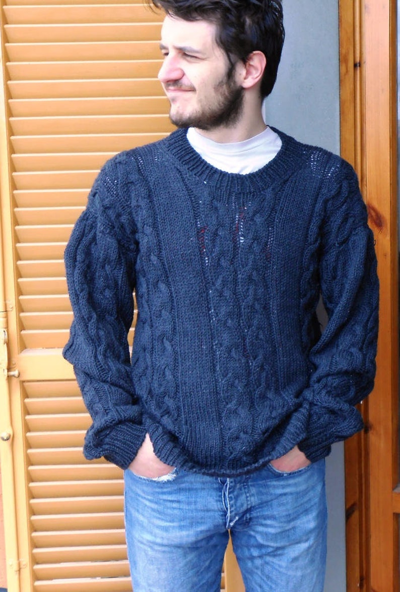 May include: A dark blue cable knit sweater with a crew neck. The sweater is made of a soft, comfortable material and has a relaxed fit.