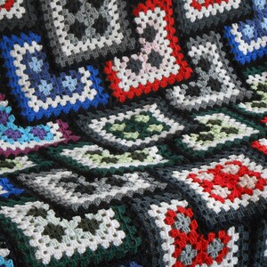 May include: A colorful crocheted blanket with squares in various colors, including red, white, blue, green, and black.