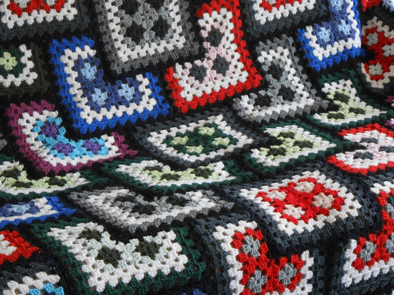May include: A colorful crocheted blanket with squares in various colors, including red, white, blue, green, and black.