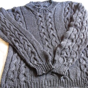 May include: A gray cable knit sweater with a crew neck.