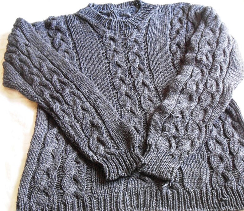May include: A gray cable knit sweater with a crew neck.