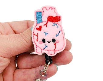 May include: A pink felt heart with red and blue embroidery, a cute face, and a black retractable badge reel.