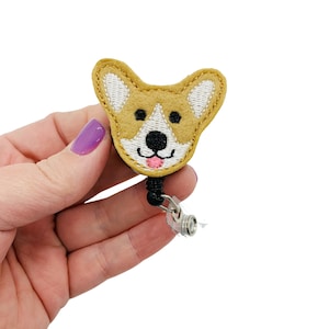 May include: A brown and white felt corgi face badge reel with a black retractable cord and a clear plastic clip.