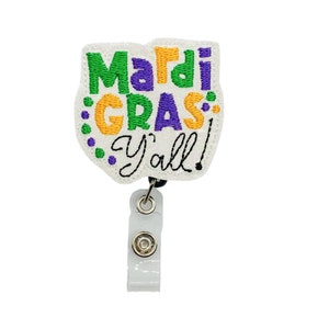May include: White Mardi Gras themed badge holder with a purple, green, and gold embroidered design that says "Mardi Gras Y'all!"