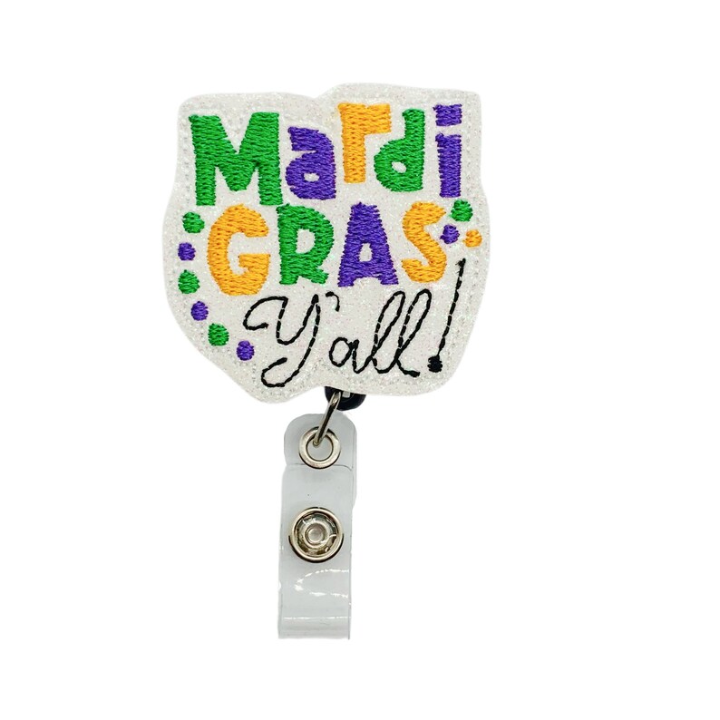 May include: White Mardi Gras themed badge holder with a purple, green, and gold embroidered design that says "Mardi Gras Y'all!"