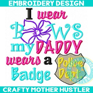 May include: Embroidered design with the text "I wear bows my daddy wears a police badge". The design features a purple flower, a pink police badge, and the text in various colors.