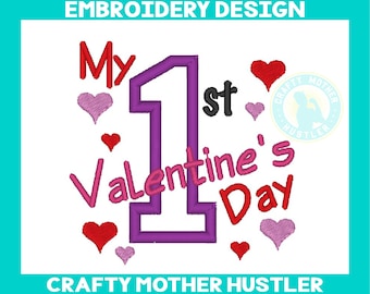 Op de afbeelding: Borduurwerk met de tekst "My 1st Valentine's Day" in roze en rode letters. Het cijfer 1 is paars en omringd door roze harten. Het ontwerp bevat ook de tekst "Crafty Mother Hustler" in een cirkel.