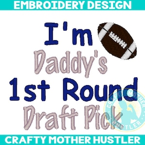 Puede incluir: Diseño bordado con el texto "I'm Daddy's 1st Round Draft Pick" en letras azules y grises. Un balón de fútbol marrón con cordones blancos está en la esquina superior derecha.
