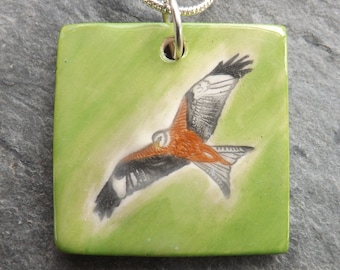 Handmade Ceramic Red Kite Pendant, striking green grass background, bird lover gift