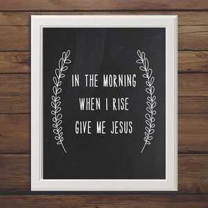 May include: A framed print with a white border and a black background. The text "IN THE MORNING WHEN I RISE GIVE ME JESUS" is written in white, surrounded by a white floral design.