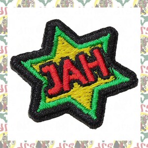 May include: Embroidered star-shaped patch with the word "JAH" in red letters. The star has a yellow center, green border, and black outline. The patch is likely for clothing or accessories.