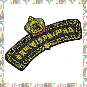 May include: A black embroidered patch featuring a curved rectangular shape with a decorative border and yellow text. At the top, a small crown-like emblem is stitched in yellow, green, and red thread. The patch has a black background.