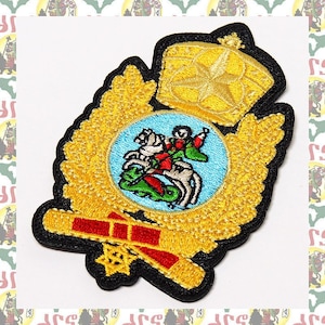 May include: A gold embroidered patch with a crown, a winged design, and a central image of a knight on horseback. The patch is on a black background.