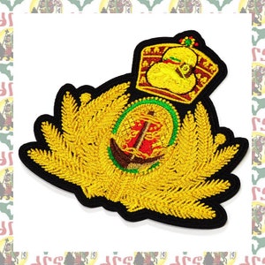 May include: Embroidered patch featuring a gold crown and anchor design. The patch has a black border and is adorned with gold thread, creating a detailed and textured appearance. The central emblem includes a red anchor and intricate detailing.
