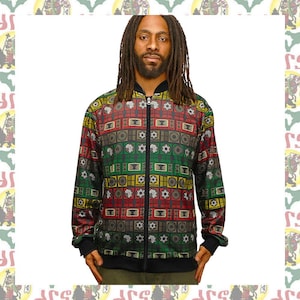 Puede incluir: Chaqueta con cremallera multicolor con un patrón geométrico en rojo, verde, amarillo y marrón. La chaqueta tiene cuello, puños y dobladillo negros. El patrón incluye varios símbolos y formas.