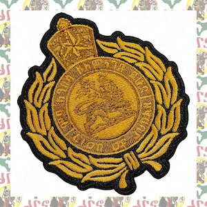 May include: A circular embroidered patch featuring a gold lion emblem at the center, surrounded by a gold laurel wreath and topped with a gold crown. The text "THE ARMY CADET FORCE" and "REGION OF JAMAICA" is stitched in gold thread around the lion.