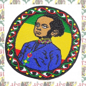 May include: Embroidered patch featuring a portrait of a young person with dark skin and black hair, wearing a blue and gold robe. The portrait is surrounded by a black, red, green, and white circular frame.