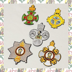 May include: Five embroidered patches featuring a gold crown, a lion, a man in a military uniform, and a wheel. The patches are on a white background.