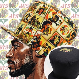 May include: A flat-top hat featuring a vibrant grid pattern of illustrated figures and symbols in yellow, orange, green, and black. A second view shows a solid black hat with a small embroidered lion emblem on the top crown surface.