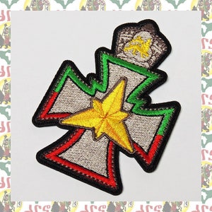 Puede incluir: Un parche bordado en verde, rojo y amarillo con una estrella y una corona. El parche tiene forma de cruz.