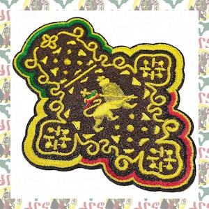 May include: An embroidered patch featuring a central yellow lion holding a cross, set against a dark brown background with intricate yellow scrollwork borders, accented by green and red stitching along the outer edges of the irregular shape.