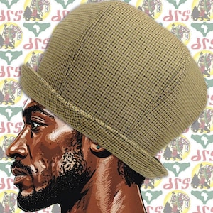 Puede incluir: Un sombrero con estampado de pata de gallo en color canela y negro con ala corta. El sombrero está sobre un fondo con un patrón repetido de un león y la palabra "JSP".