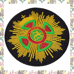 Puede incluir: Un parche bordado negro con un diseño de estrella dorada. El centro del parche presenta un círculo rojo y verde con una figura estilizada y el texto "SAINT VINCENT".