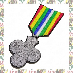 May include: A silver embroidered patch of a clover with a ribbon in red, yellow, green, blue, and white.