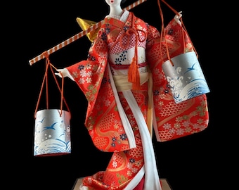 Japanese Geisha in Kimono Carrying Water Buckets Doll. This gorgeous and adorable geisha doll. Dressed in an opulent traditional costume.