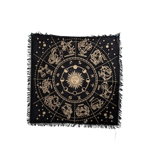 May include: Black tapestry with a gold zodiac wheel featuring the twelve signs of the zodiac, the sun, and the moon. The tapestry has a fringed edge.