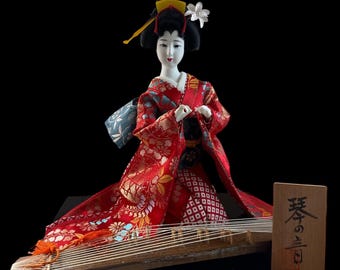 Japanese Geisha in Kimono Playing Koto. This doll is both gorgeous and adorable. The doll is dressed in an opulent traditional costume.