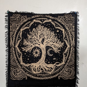 May include: Black tapestry with a gold tree of life design. The tree is surrounded by a circle of stars, a sun, and a moon. The background is black with a gold mandala design.