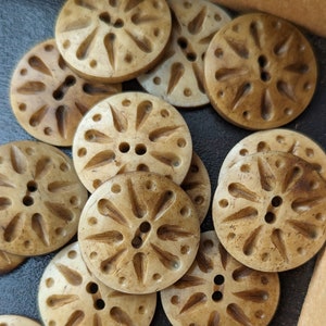 May include: A collection of 10 beige and brown decorative buttons with a floral design. The buttons are made of a natural material and have a rustic look.