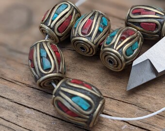 May include: A string of six oval-shaped beads with intricate designs. The beads are made of brass and feature turquoise and red accents.