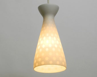 May include: A white ceramic pendant light with a dotted pattern. The light is turned on and illuminates the room.