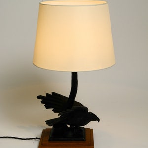 May include: A black bird lamp with a white lampshade. The bird is perched on a wooden base.