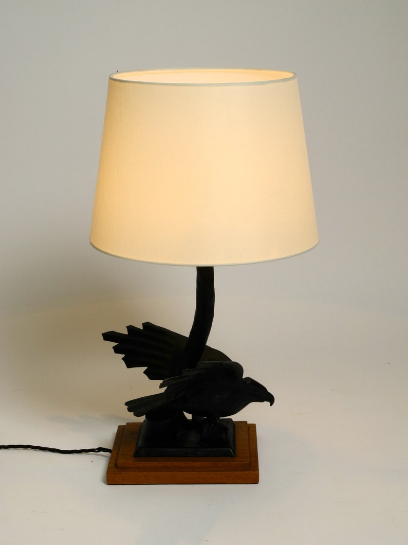 May include: A black bird lamp with a white lampshade. The bird is perched on a wooden base.