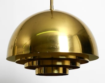 May include: A gold-toned, tiered pendant light fixture with a large, rounded dome top. The light fixture has a modern, minimalist design.