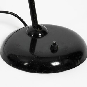 Puede incluir: L&aacute;mpara de escritorio negra con base redonda y cable negro. La l&aacute;mpara tiene un solo interruptor en la base.