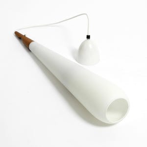 May include: A white cone-shaped pendant light with a wooden base and a white cord. The light is hanging from the ceiling.