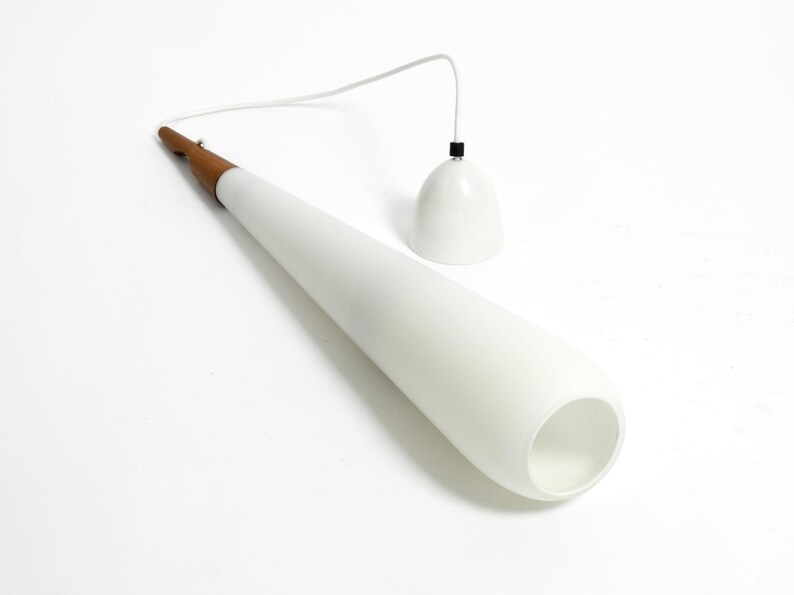 May include: A white cone-shaped pendant light with a wooden base and a white cord. The light is hanging from the ceiling.