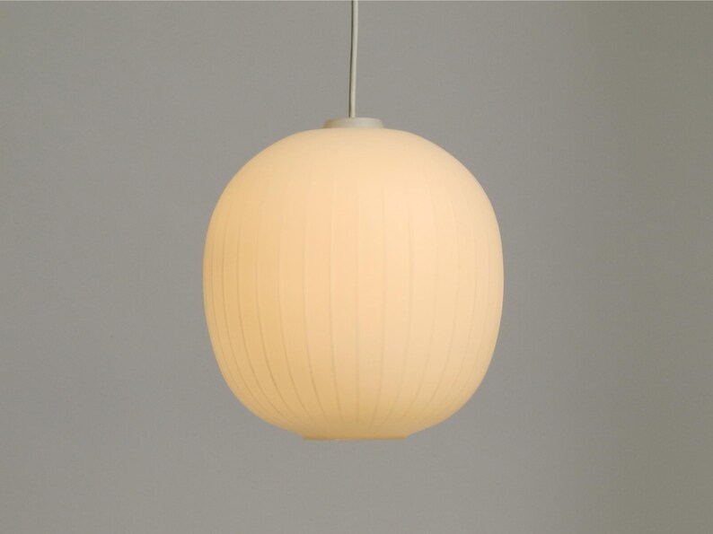 Puede incluir: Una l&aacute;mpara colgante redonda de color blanco roto con una textura acanalada. La l&aacute;mpara cuelga de un fino cable blanco y emite un brillo suave y c&aacute;lido. El dise&ntilde;o es simple y moderno, adecuado para varios estilos de interior.