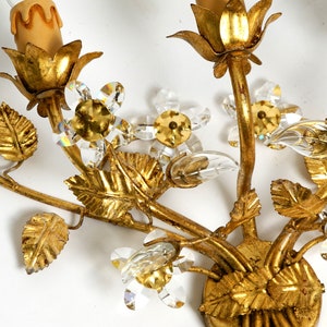 May include: Gold metal wall sconce with a floral design. The sconce features leaves, flowers, and crystal accents.