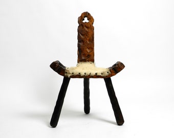 Beautiful Mid Century three-legged stool with backrest made of solid wood in black-brown with cowhide seat