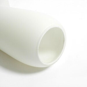 May include: White ceramic vase with a smooth, rounded shape and a wide opening. The vase is designed with a unique twist in the middle, creating a modern and elegant look.