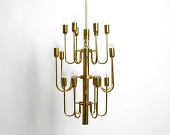 May include: A gold-toned metal chandelier with 16 light bulbs. The chandelier has a unique design with multiple arms that curve upwards.