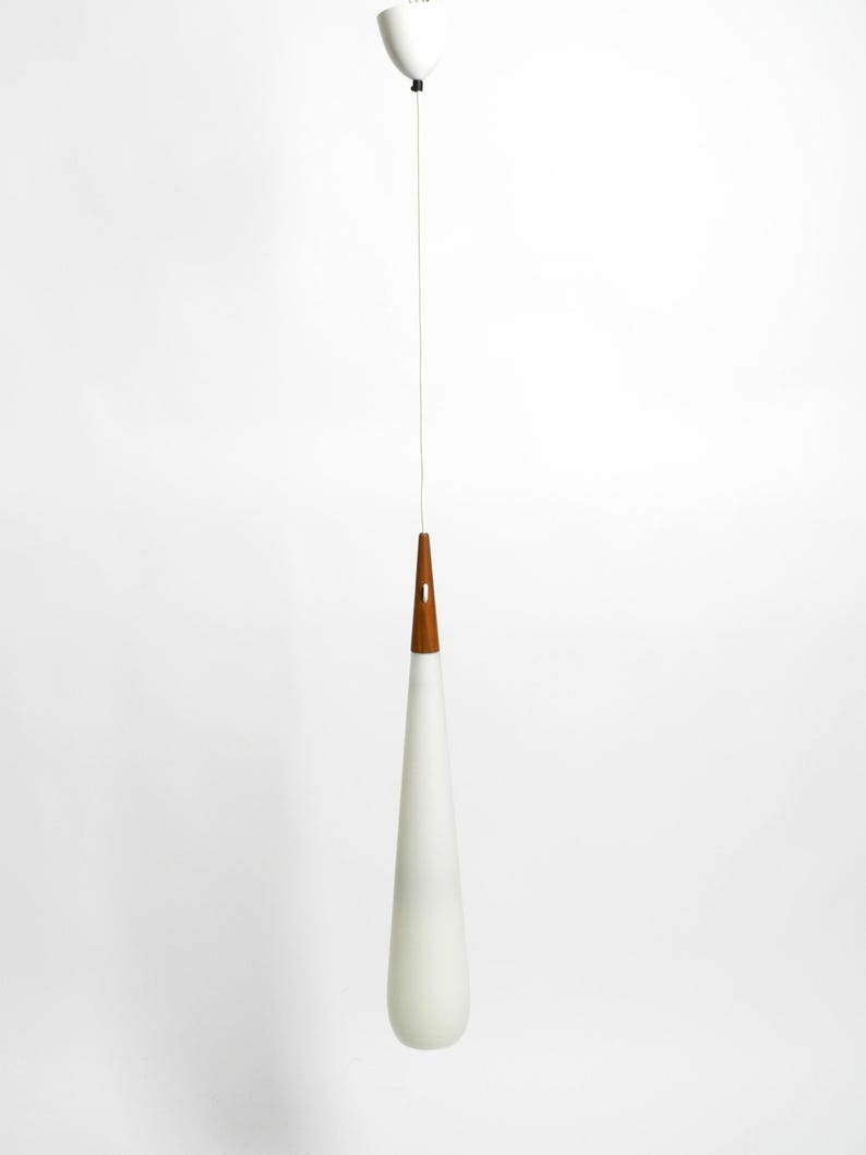 May include: A white teardrop-shaped glass pendant light with a wooden top hangs from a white ceiling.