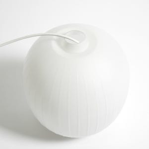 Puede incluir: L&aacute;mpara colgante esf&eacute;rica blanca con textura acanalada. La l&aacute;mpara tiene un acabado liso y mate y un cable blanco que se extiende desde la parte superior. El dise&ntilde;o es minimalista y moderno, adecuado para varios estilos de interior.