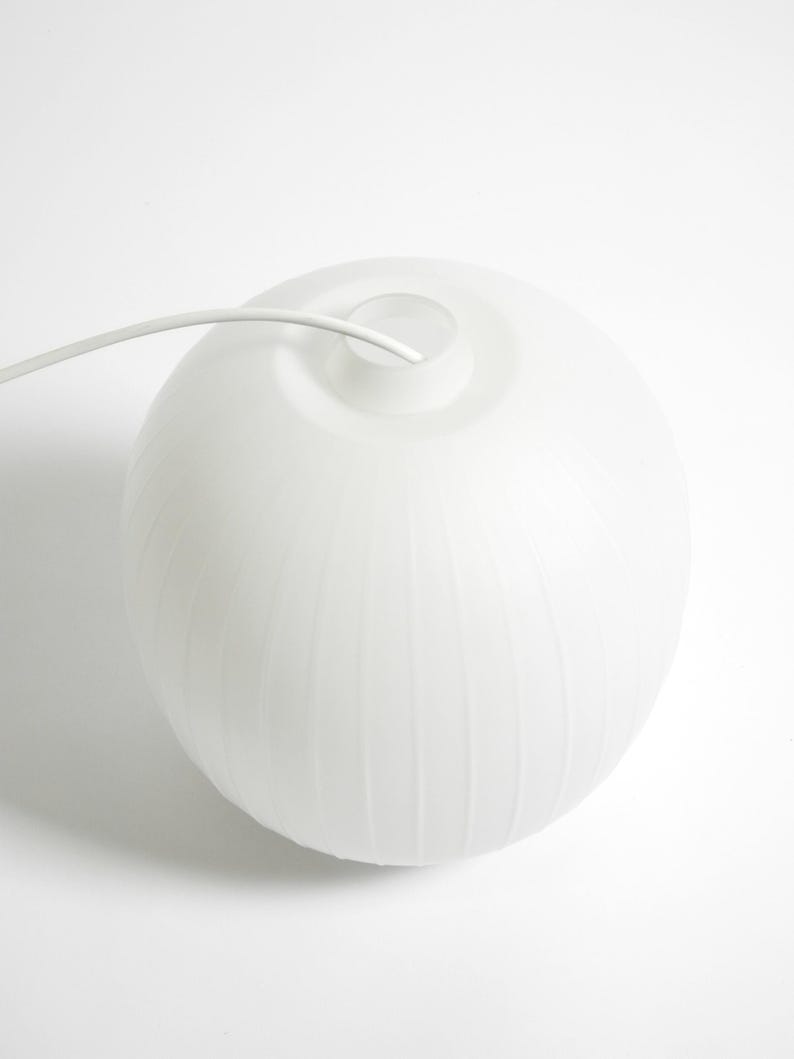 Puede incluir: L&aacute;mpara colgante esf&eacute;rica blanca con textura acanalada. La l&aacute;mpara tiene un acabado liso y mate y un cable blanco que se extiende desde la parte superior. El dise&ntilde;o es minimalista y moderno, adecuado para varios estilos de interior.