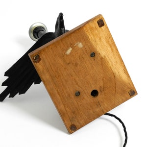 May include: A black metal lamp with a bird design and a wooden base. The lamp has a cord and a light bulb.